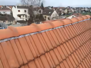 Faîtage à sec d’une toiture en tuiles neuves, closoir ventilé visible sous les tuiles faîtières