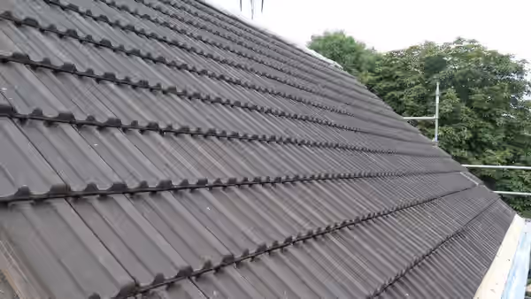 Toiture en tuiles béton terminée, vue le long du versant jusqu’à l’arêtier